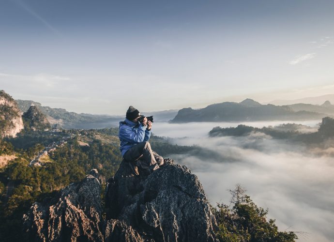 homme en haut d'une montagne prenant des photos