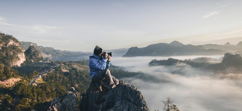 homme en haut d'une montagne prenant des photos